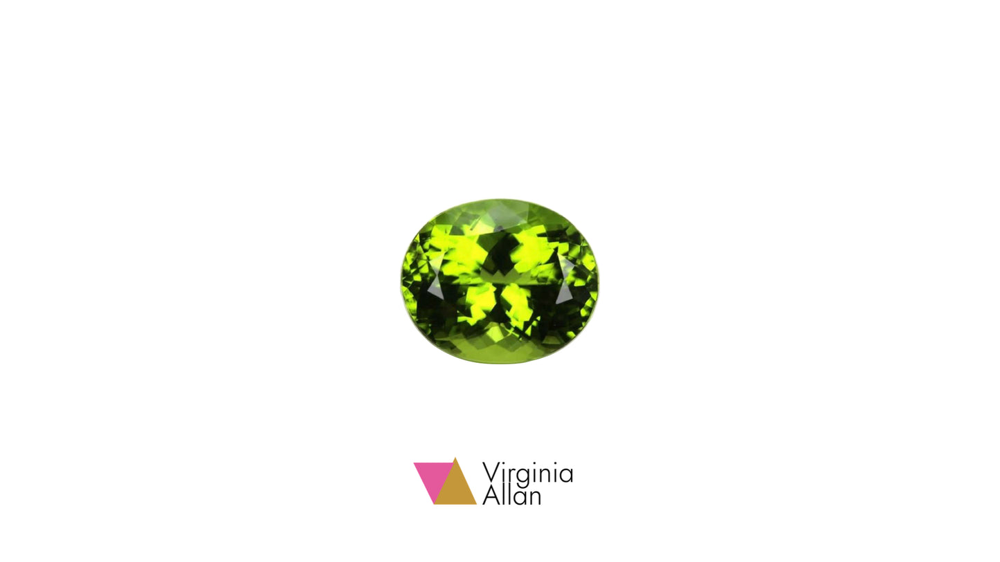 An oval-cut green gemstone with faceted lime-green and yellow-green tones, centered on a plain white background with the Virginia Allan logo below it.